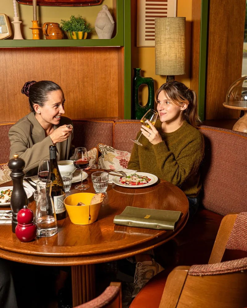Two guests chatting over a drink and a plate at Billy